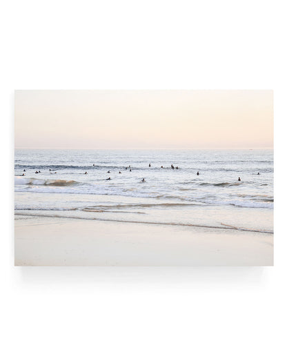 San Clemente surf wall art featuring surfers waiting in gentle ocean waves at sunset, with soft pastel sky tones and rolling waves along a sandy California shoreline.