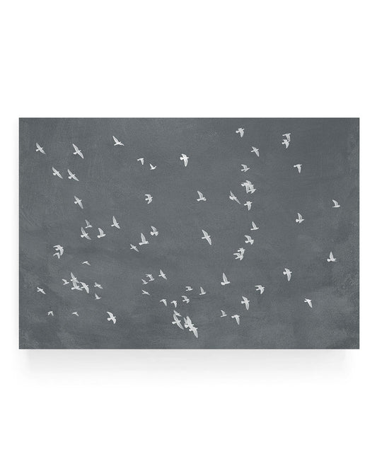 Minimalist graphite photograph of a flock of white birds flying across a dark gray sky, high contrast aerial bird silhouettes in motion.