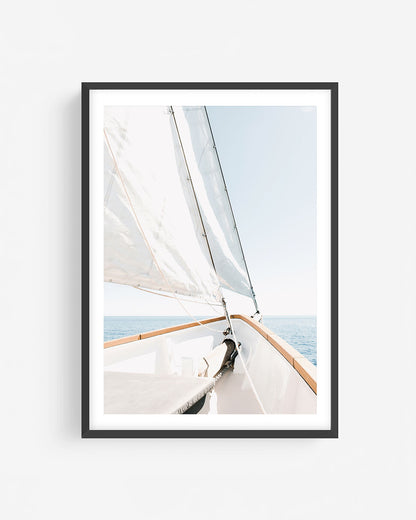 Fine art sailboat photograph in a black frame showing the bow of a sailboat with white sails and open ocean under a clear sky.