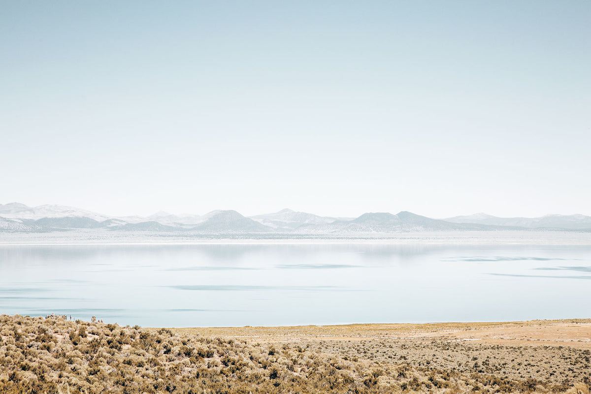 Mono Lake landscape photography featuring calm blue water, distant mountains, and golden high-desert sagebrush in California.