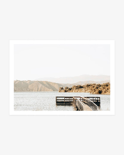 Lake Cachuma wall art featuring a wooden dock extending into calm water with sunlit hills and hazy mountains across the Santa Ynez Valley.
