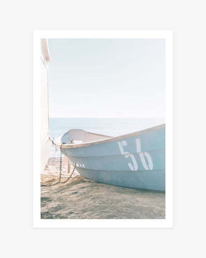 an Clemente beach wall art featuring a pale blue rescue boat marked 56 resting on the sand beside the Pacific Ocean.