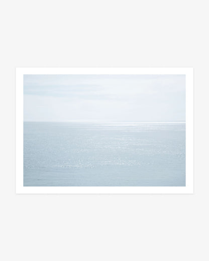 Malibu ocean photography featuring sunlight shimmering across calm blue Pacific water beneath a pale, softly clouded coastal sky.