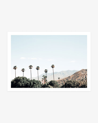 Palm Springs California landscape wall art featuring tall palm trees against rugged desert mountains beneath a pale blue sky.