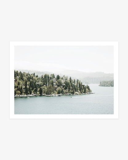 Lake Arrowhead wall art featuring lakeside cabins nestled among evergreen trees beside calm mountain water and hazy California hills.