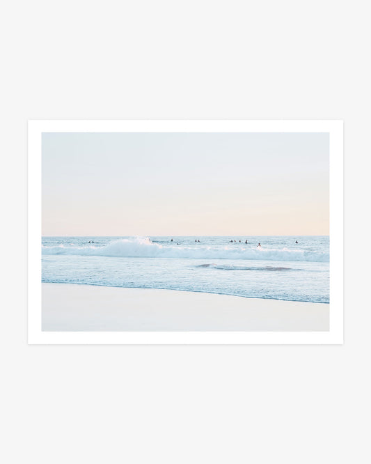San Clemente surfer wall art featuring a distant lineup beyond a breaking Pacific wave beneath a pale blue and blush coastal sky.