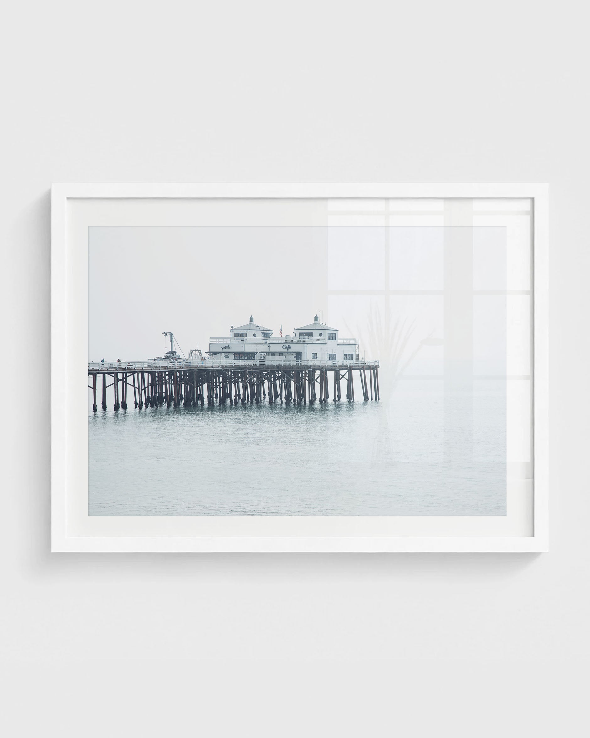 Malibu beach pier wall art with wooden pier structure, calm ocean water, and soft foggy coastal sky in neutral tones.