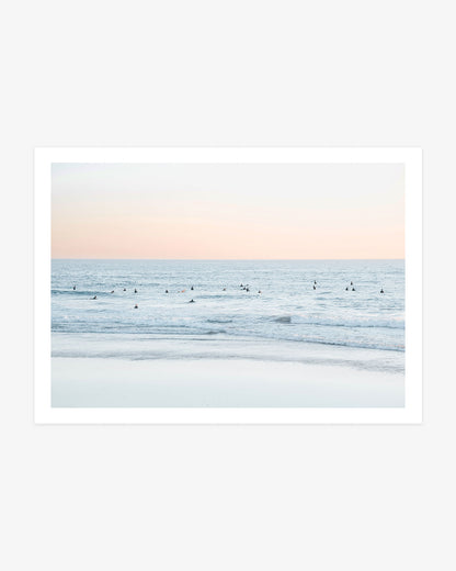 San Clemente surfer photography featuring a group of surfers waiting beyond gentle Pacific waves beneath a soft peach-colored sky.