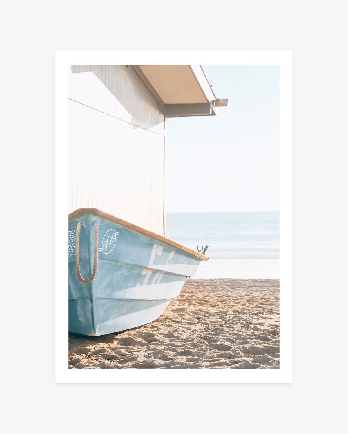 San Clemente beach wall art featuring a weathered blue rescue boat resting on the sand beside a white beach building and the Pacific Ocean.