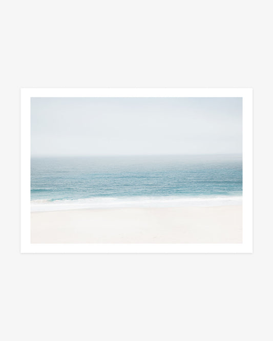 Pacific Ocean wall art featuring a soft blue horizon, gentle white surf and a pale sandy beach in calm neutral coastal tones.