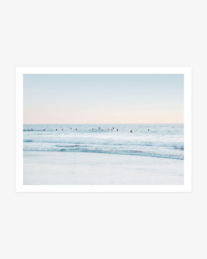 San Clemente surf wall art featuring a wide lineup of surfers waiting in pale blue Pacific water beneath a soft blush coastal sky.