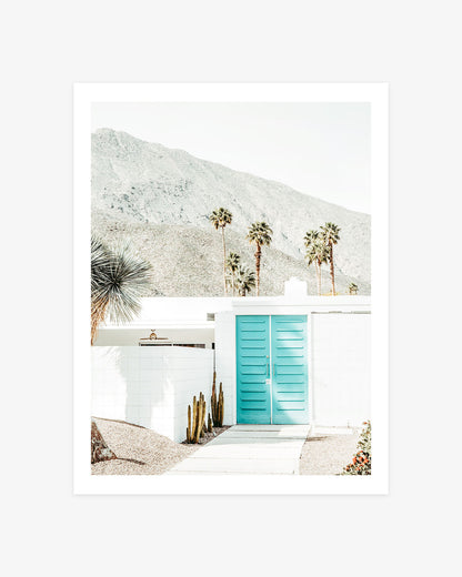 Turquoise double doors on a white Palm Springs home with desert plants, tall palms, and the San Jacinto Mountains.