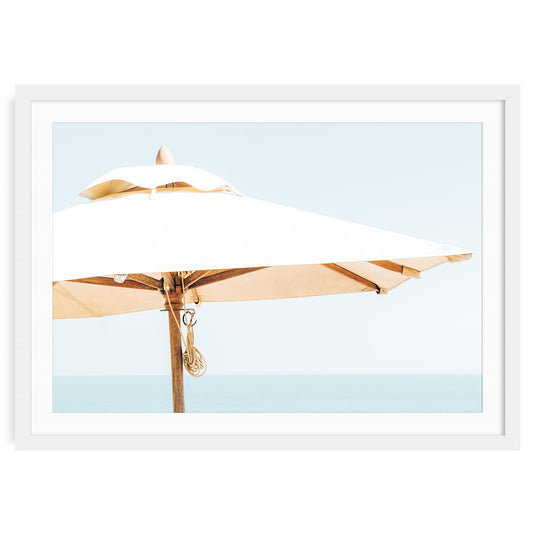 Minimalist beach umbrella print featuring a single striped umbrella on a sandy coastal shore under soft summer light, perfect for serene coastal wall decor.