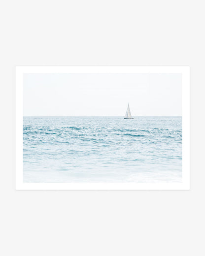 Newport Beach sailboat photography featuring a single white sailboat crossing the blue Pacific beneath a pale open sky.