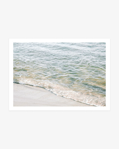 Newport Beach ocean photography featuring a gentle wave meeting pale sand in soft blue, green and warm neutral tones.