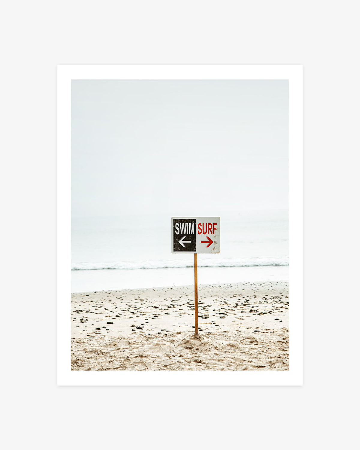 Malibu Beach photography featuring a weathered swim and surf sign standing on a pale sandy shore beside the Pacific Ocean.
