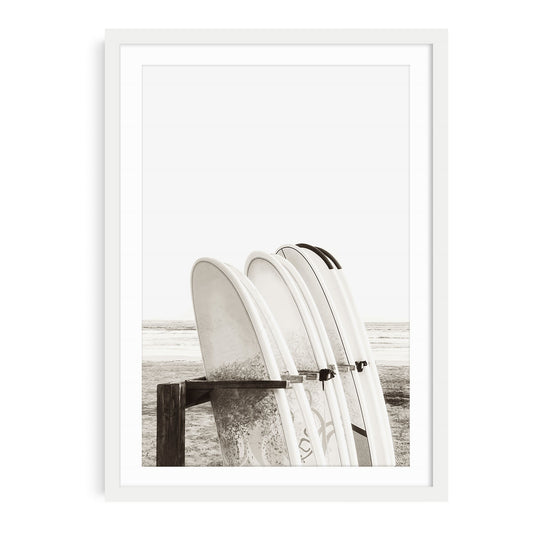 Minimalist beach wall art featuring multiple surfboards organized in a wooden surfboard stand near the sand with neutral beige tones and soft coastal lighting.