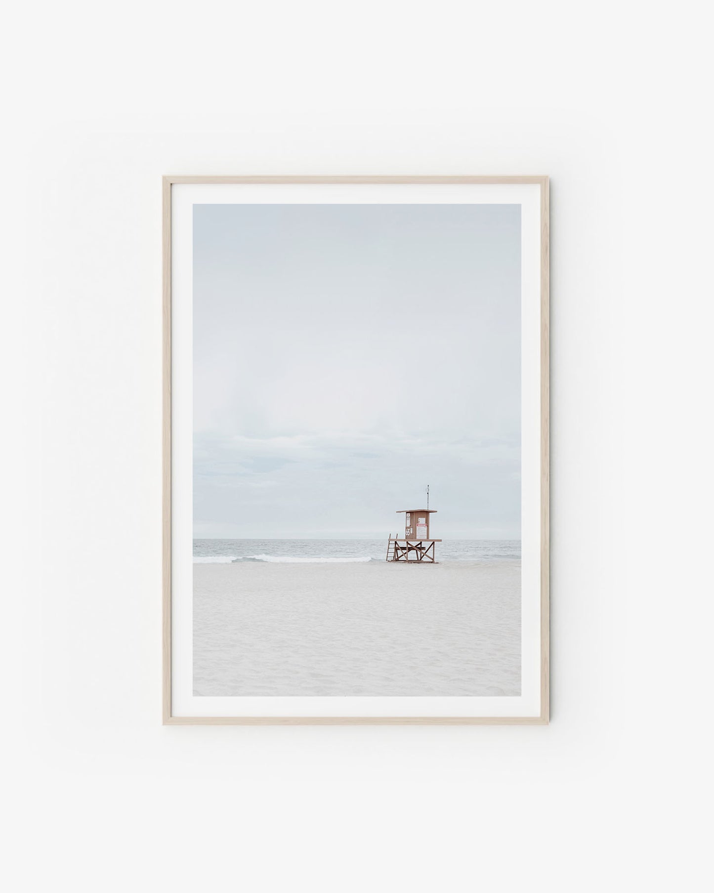 Neutral coastal scene with soft sand tones and a calm horizon in pale, airy light.