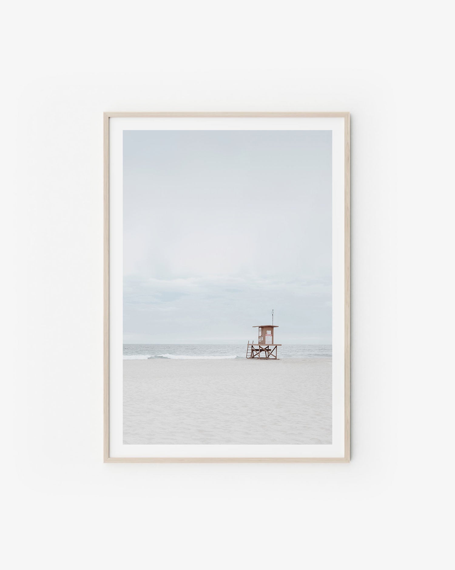 Neutral coastal scene with soft sand tones and a calm horizon in pale, airy light.