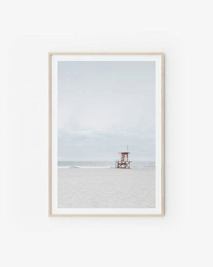 Neutral coastal scene with soft sand tones and a calm horizon in pale, airy light.