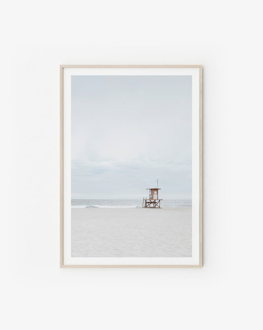 Neutral coastal scene with soft sand tones and a calm horizon in pale, airy light.