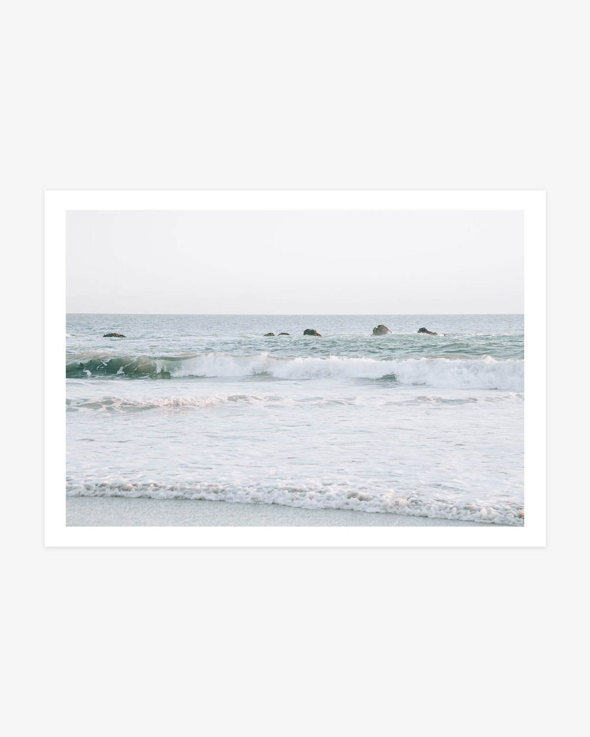 Dana Point ocean wall art featuring rolling Pacific waves and a line of coastal rocks beneath a pale Southern California sky.