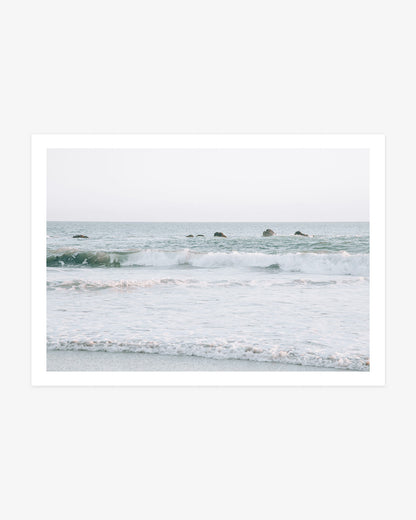 Dana Point ocean wall art featuring rolling Pacific waves and a line of coastal rocks beneath a pale Southern California sky.
