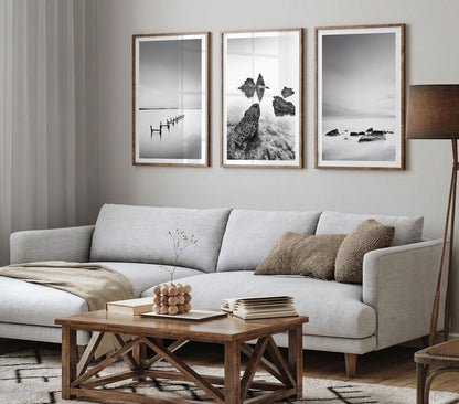 Set of 3 black and white beach wall art prints displayed in a modern living room above a sofa