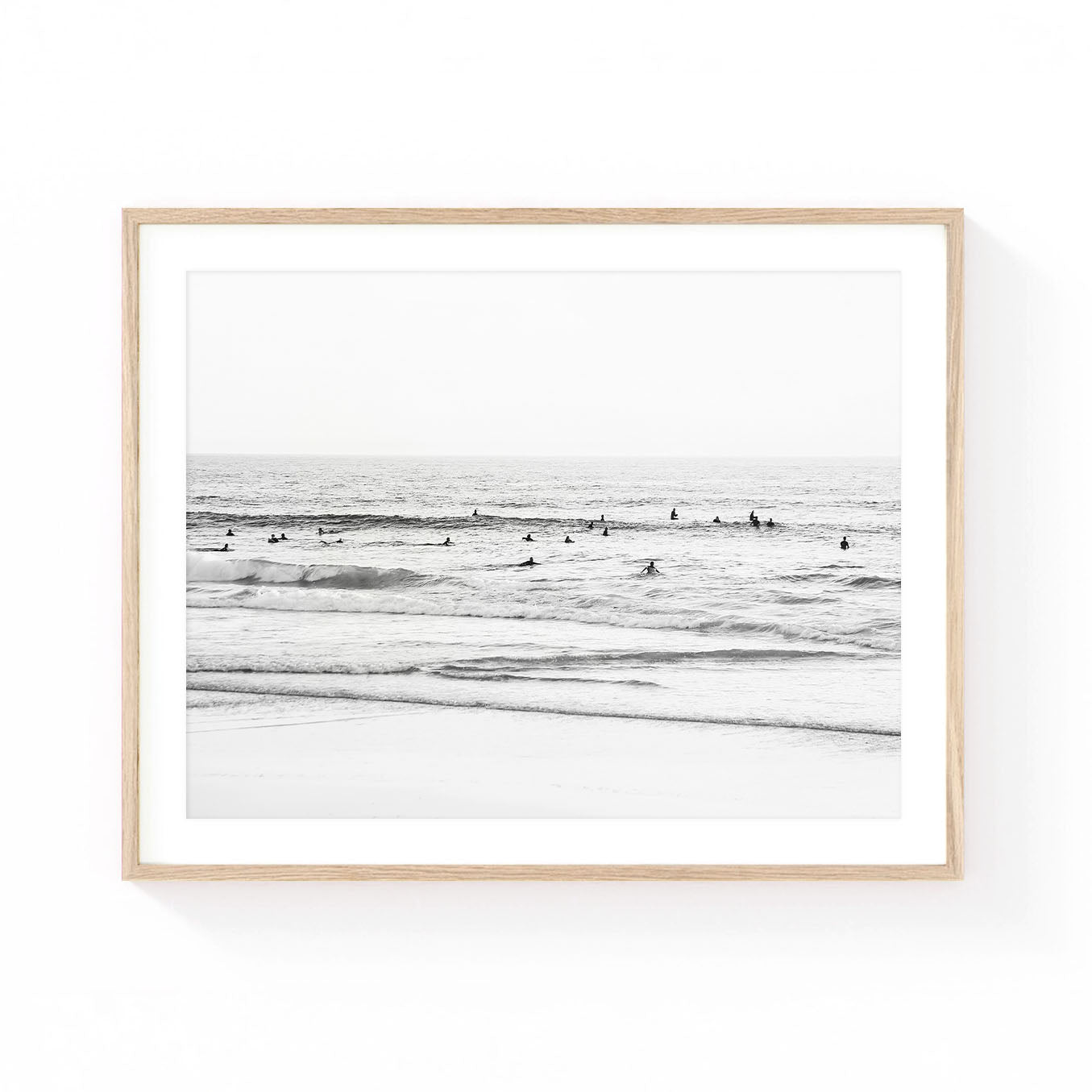 Black and white coastal wall art featuring surfers waiting beyond gentle waves, creating a calm ocean scene with minimalist beach photography and timeless coastal appeal.