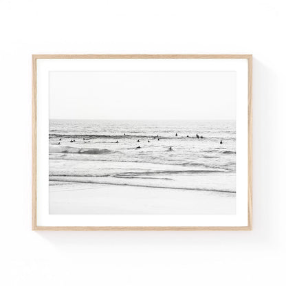 Black and white coastal wall art featuring surfers waiting beyond gentle waves, creating a calm ocean scene with minimalist beach photography and timeless coastal appeal.