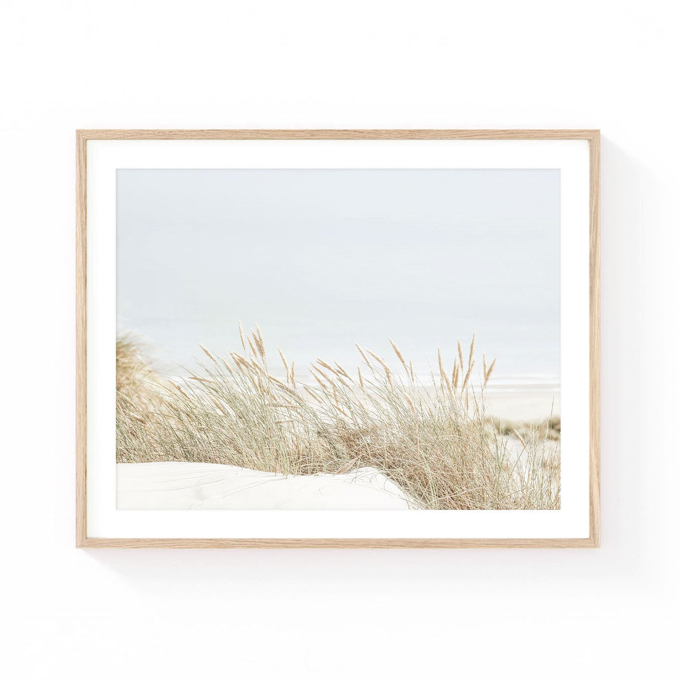 Coastal dune grass wall art featuring golden beach grass growing on sandy dunes with a soft ocean horizon in airy neutral tones.