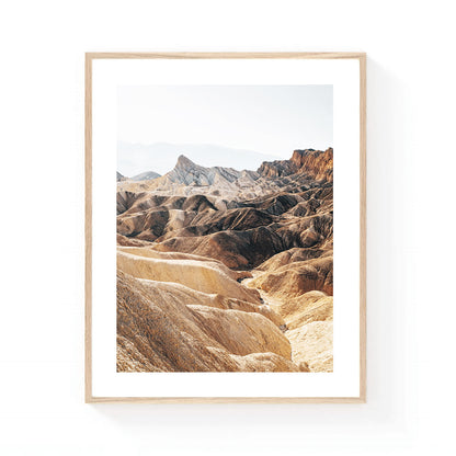Death Valley wall art featuring the layered badlands of Zabriskie Point in soft neutral tones, with sculpted desert ridges and dramatic geological formations.
