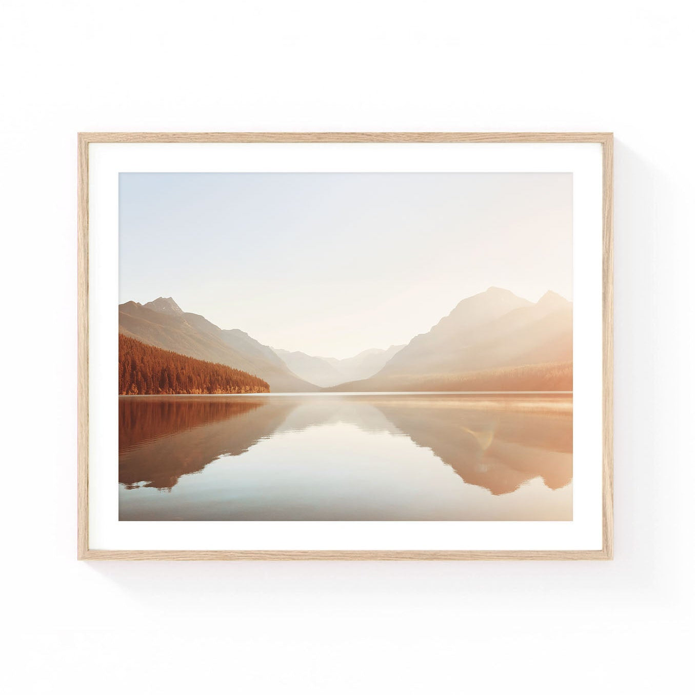 Glacier National Park wall art featuring a calm mountain lake reflecting alpine peaks, evergreen forests, and soft golden sunrise light in a serene wilderness setting.