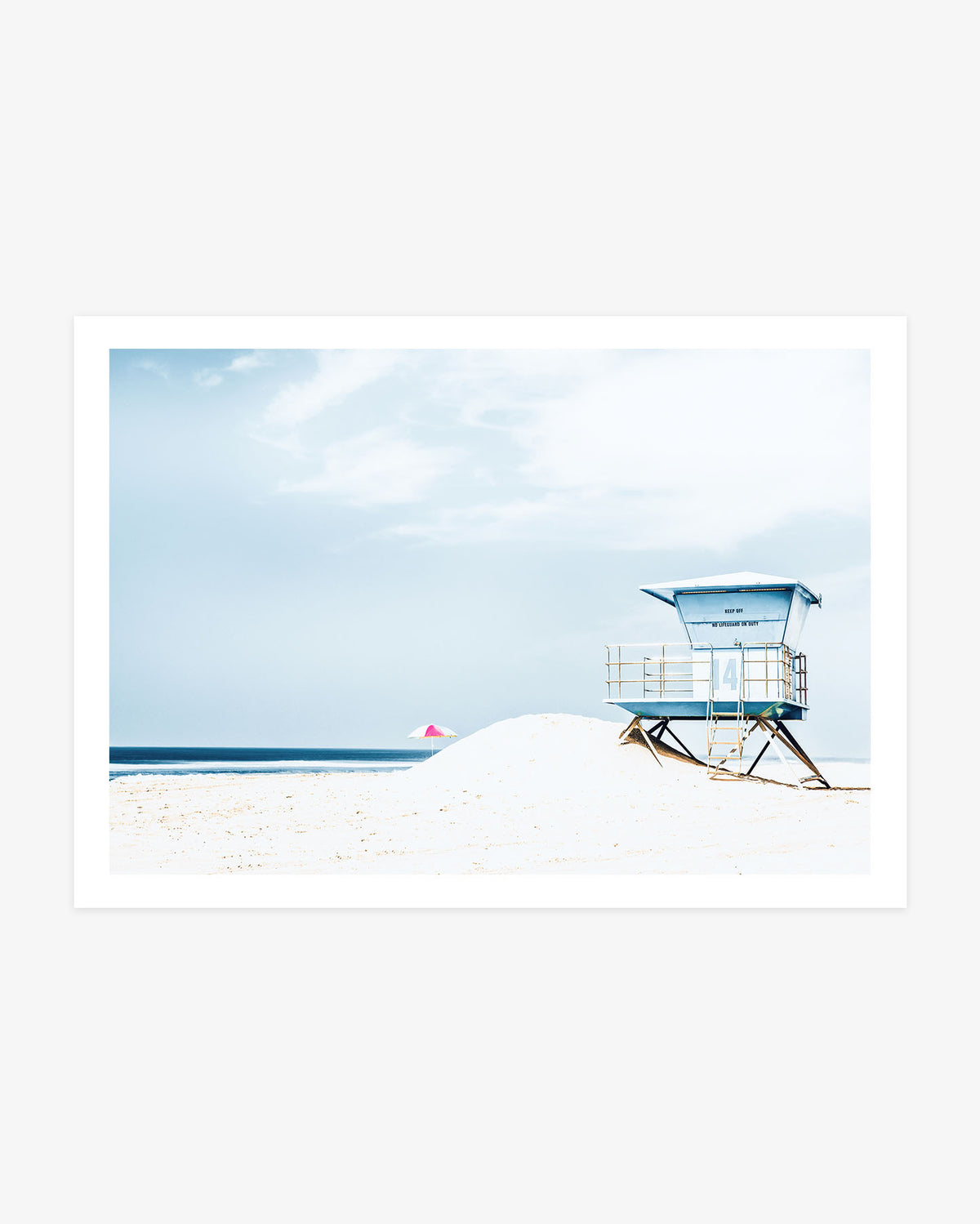 Huntington Beach wall art featuring Lifeguard Tower 14 and a colorful beach umbrella against bright sand and a soft blue coastal sky.