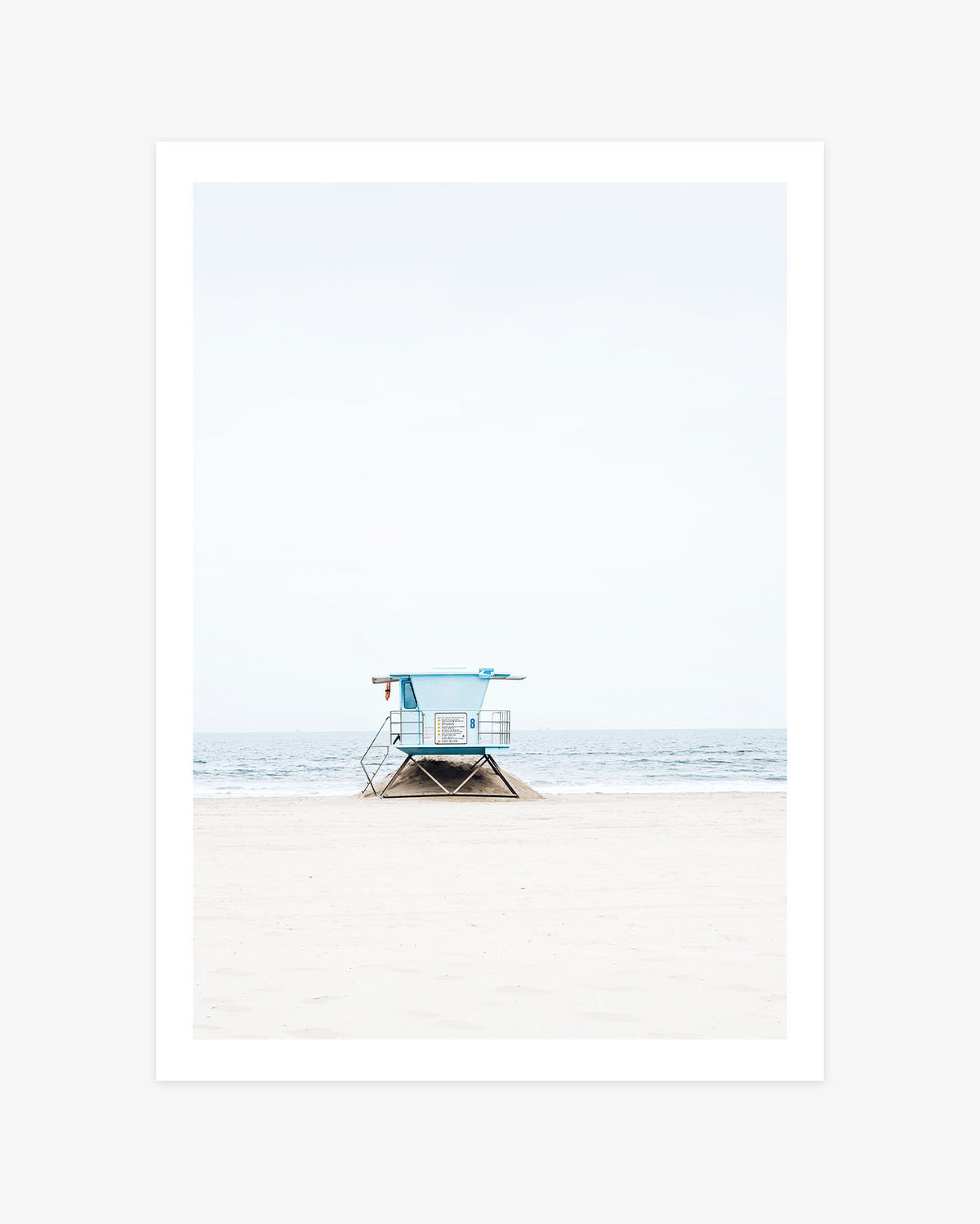 Huntington Beach lifeguard tower wall art featuring blue Tower 8 on a quiet sandy beach against the soft ocean horizon.