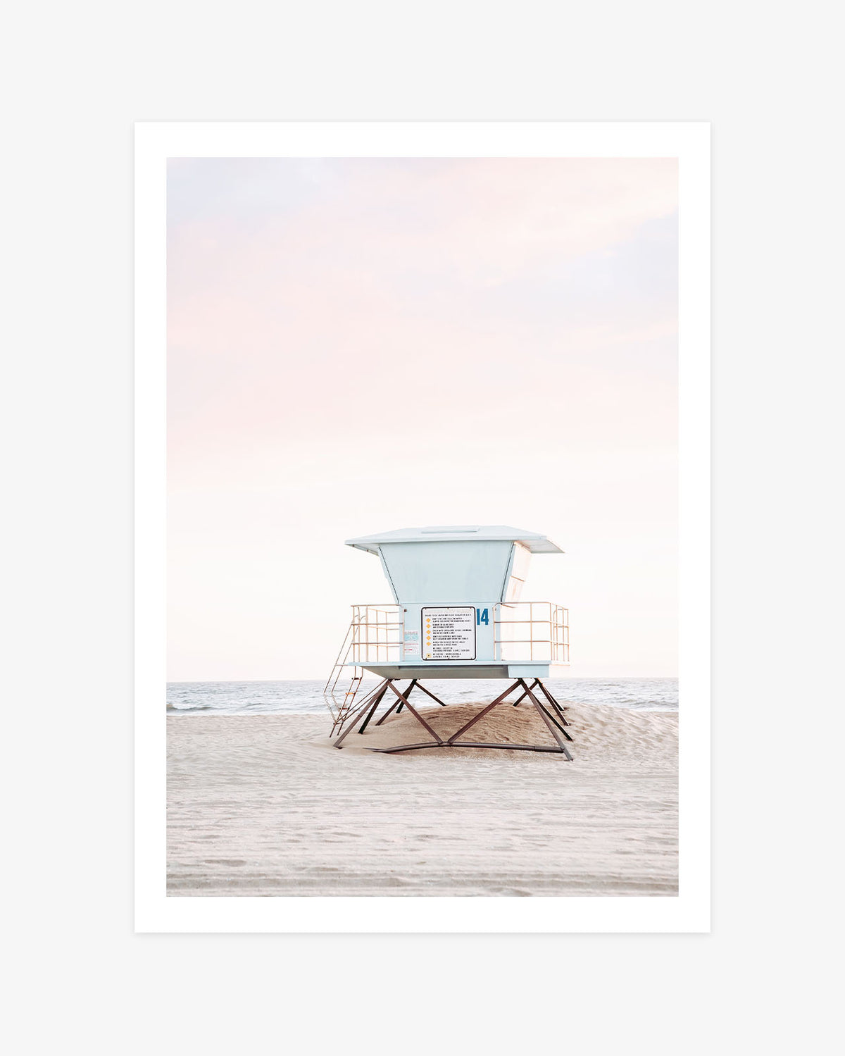 Huntington Beach wall art featuring a pastel blue lifeguard tower on a quiet sandy beach beneath a soft pink California sky.