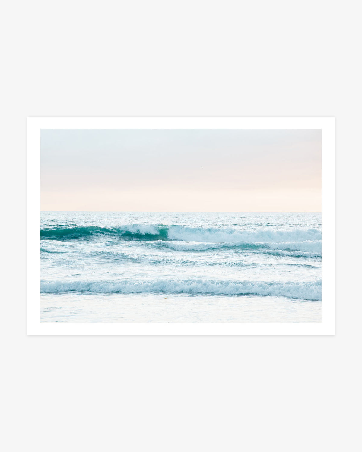 Huntington Beach ocean wall art featuring turquoise waves and white seafoam beneath a soft blue and blush California sky.