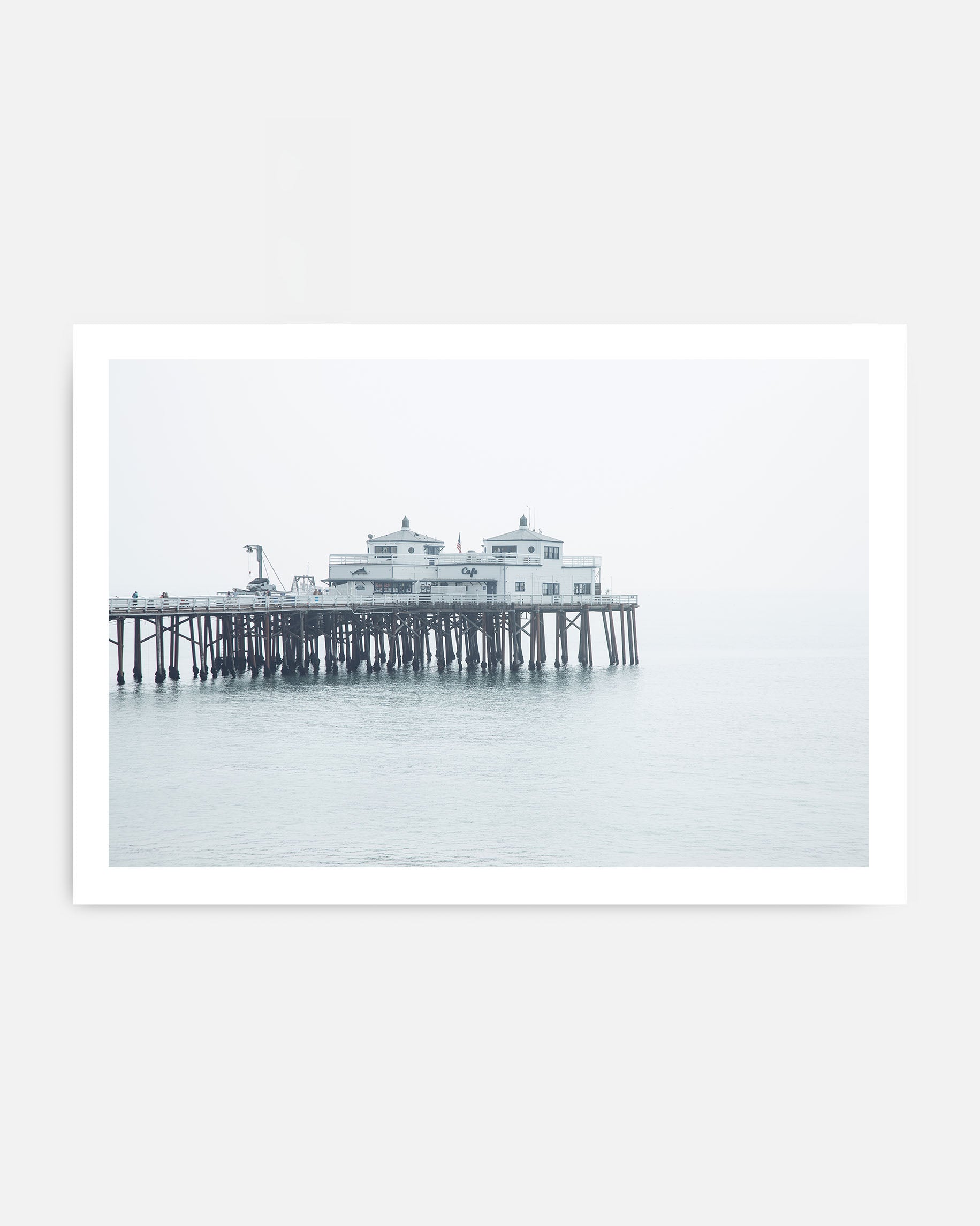 Malibu beach pier wall art with wooden pier structure, calm ocean water, and soft foggy coastal sky in neutral tones.