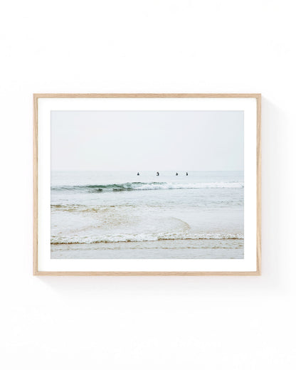Malibu surfers wall art featuring four surfers waiting in calm Pacific Ocean waters beyond gentle rolling waves, with a soft horizon, muted coastal tones, and a serene Southern California beach atmosphere.