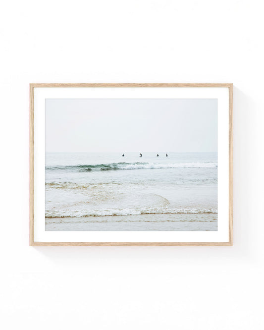 Malibu surfers wall art featuring four surfers waiting in calm Pacific Ocean waters beyond gentle rolling waves, with a soft horizon, muted coastal tones, and a serene Southern California beach atmosphere.
