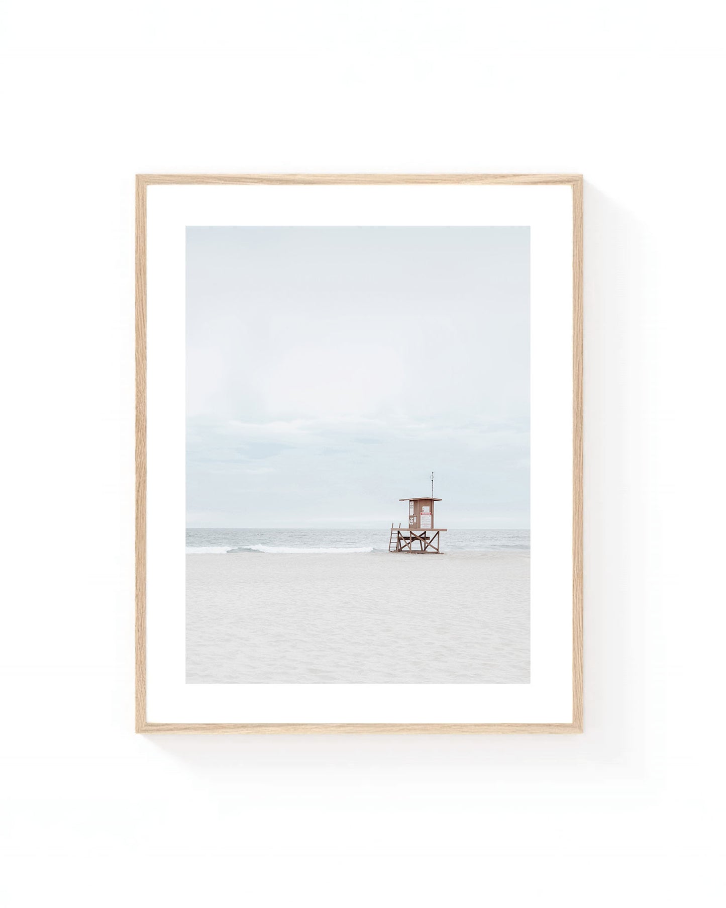Minimalist lifeguard tower wall art on a quiet sandy beach with soft gray skies, gentle ocean waves, and neutral coastal tones.