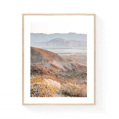 Montezuma Valley wall art featuring layered desert mountains and a winding mountain road in soft earth tones, captured in warm California desert light.