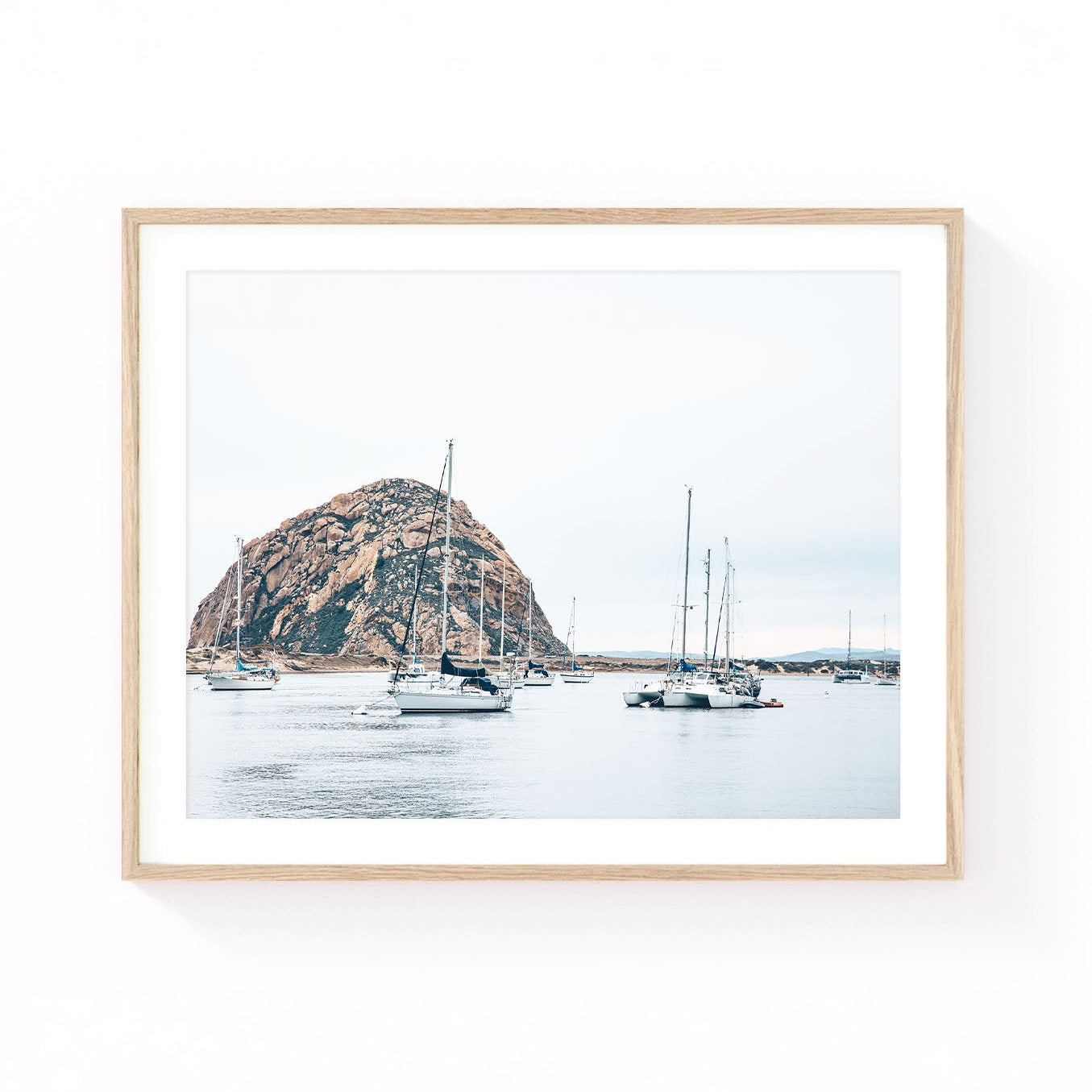 Morro Bay wall art featuring sailboats anchored in calm harbor waters with Morro Rock rising in the background beneath a soft coastal sky.
