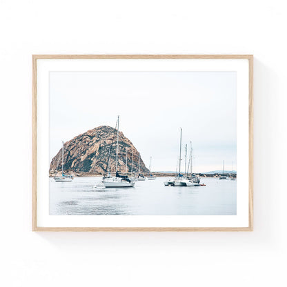 Morro Bay wall art featuring sailboats anchored in calm harbor waters with Morro Rock rising in the background beneath a soft coastal sky.
