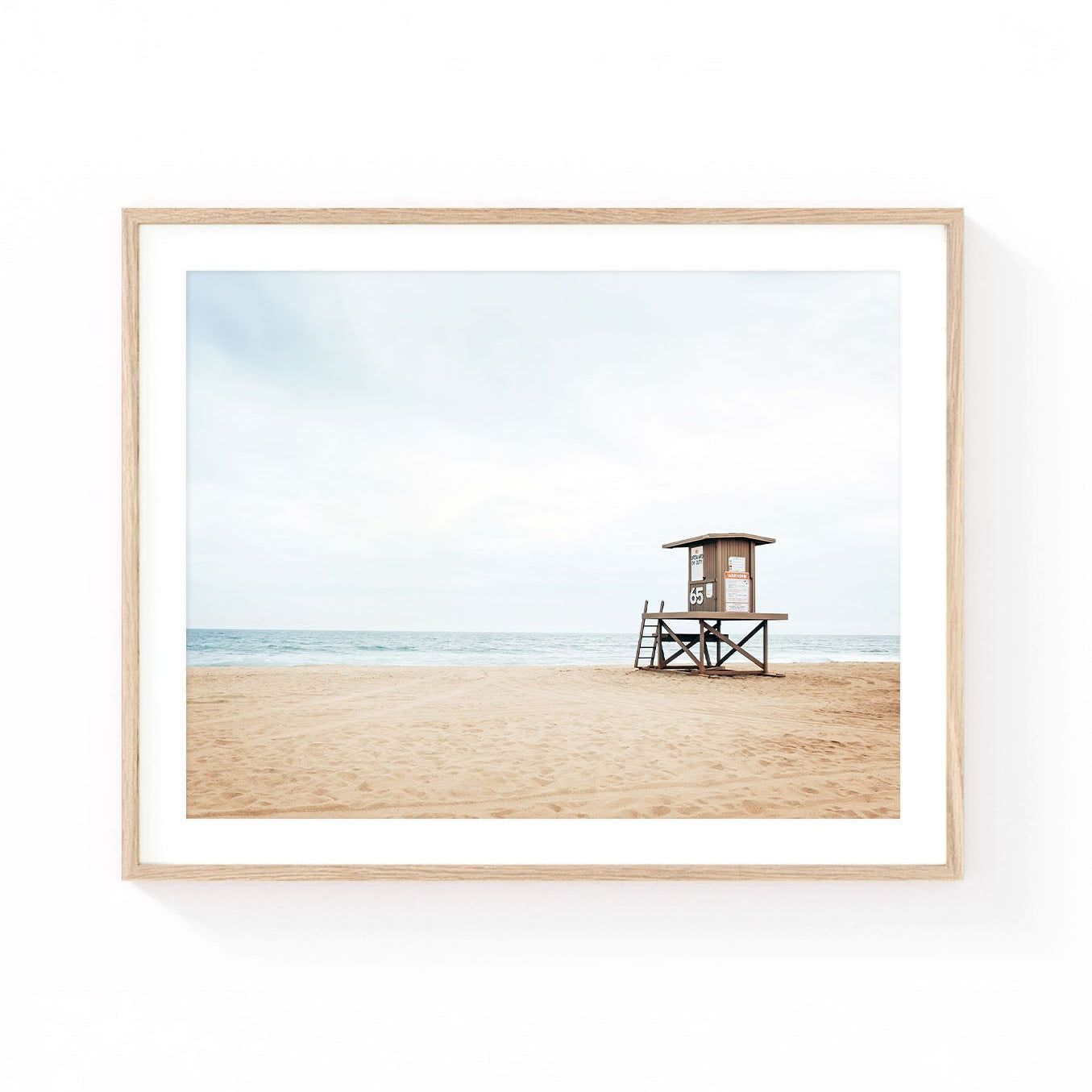 Newport Beach lifeguard tower wall art featuring Lifeguard Tower 65 on a quiet sandy beach with soft ocean waves and a cloudy coastal sky.