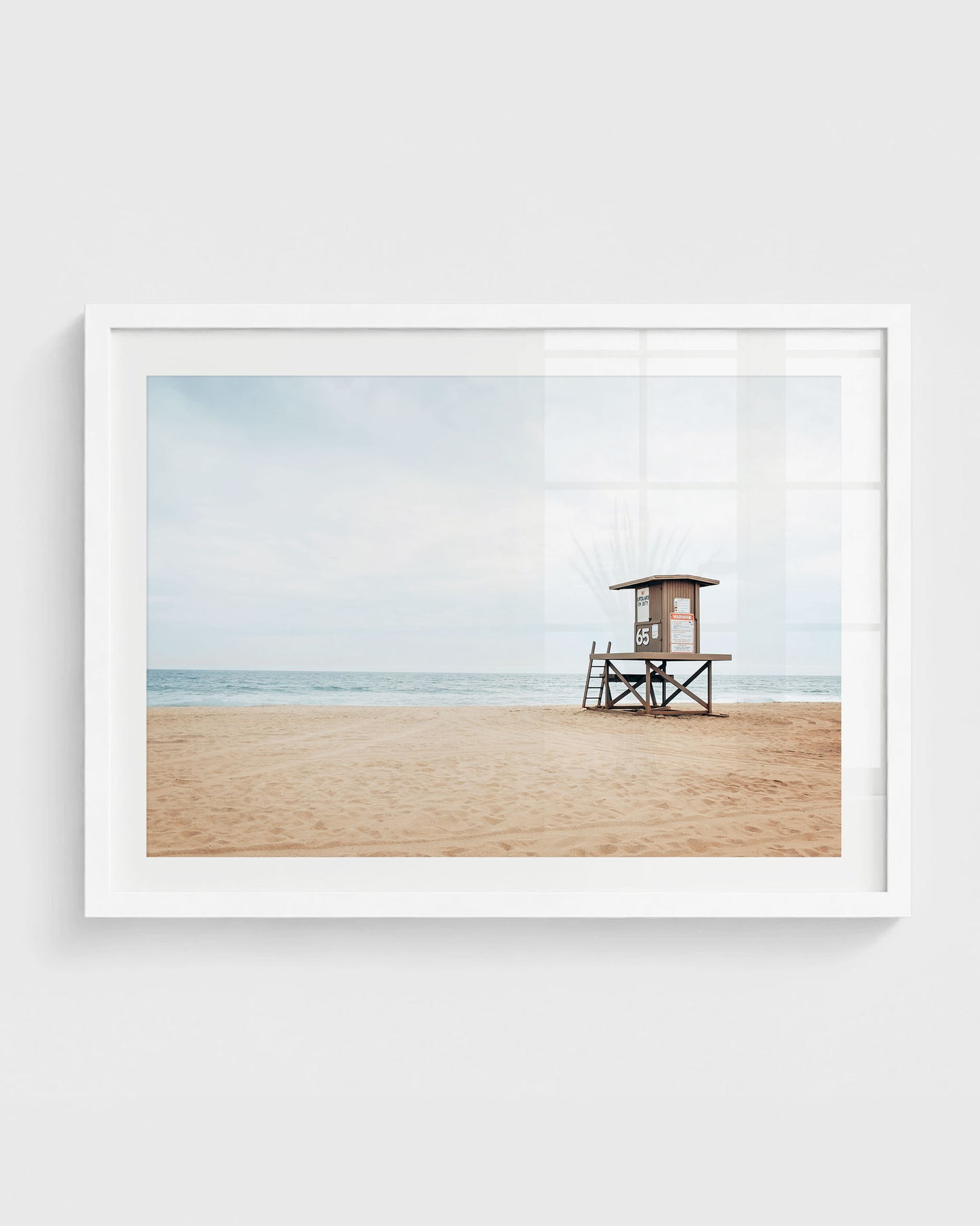 Newport Beach lifeguard tower on empty sandy beach with soft blue ocean and light cloudy sky.