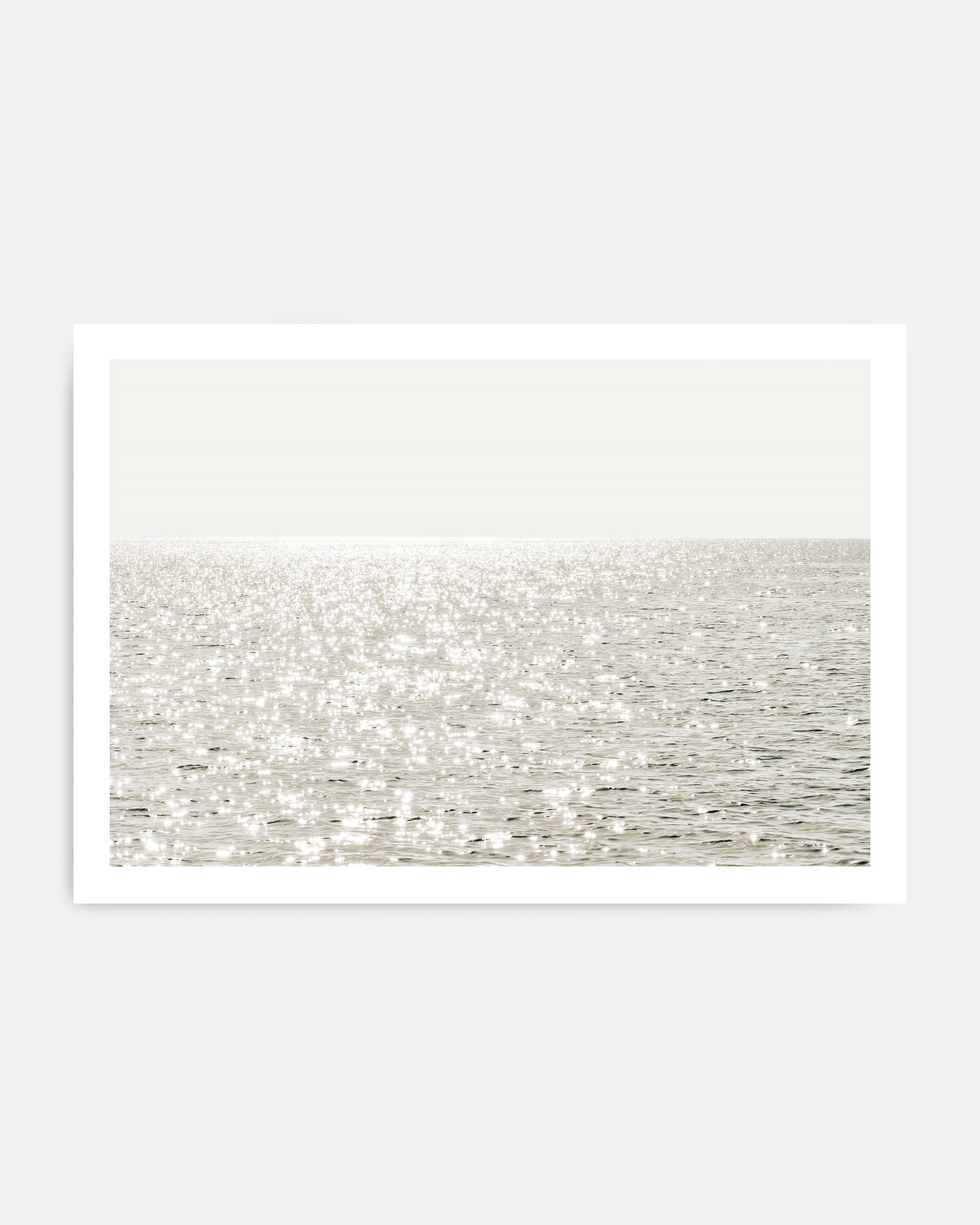 Sunlight reflecting on calm ocean water wall art in neutral coastal tones.
