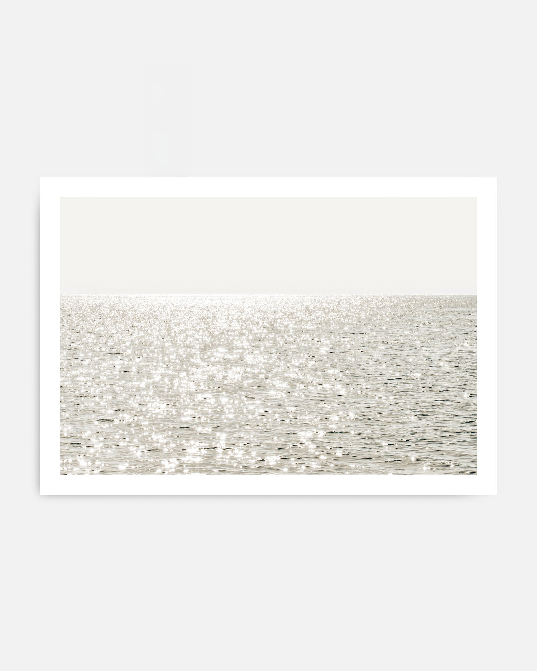 Sunlight reflecting on calm ocean water wall art in neutral coastal tones.