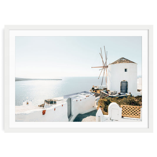 Framed Santorini wall art print in a white frame with mat, showcasing coastal Greek island scenery