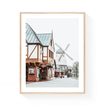 Solvang windmill wall art featuring traditional Danish-style architecture, timber-framed buildings, and a historic windmill along a charming village street in Solvang, California.